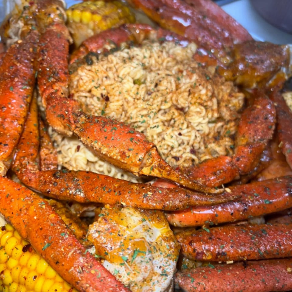 Royal Krabz seafood boil with crab legs, corn, and noodles, seasoned with spices.