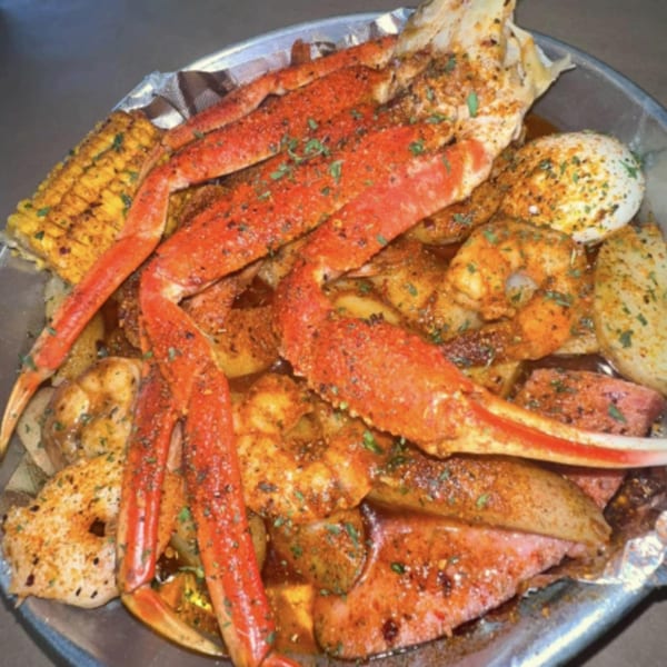 Royal Krabz seafood boil with crab legs, shrimp, corn, potatoes, and sausage in a metal pan.