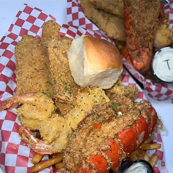 Royal Krabz seafood platter with fried shrimp, lobster, fish, fries, and a dinner roll.